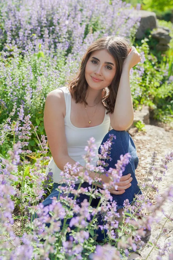 Young woman posing in field of flowers with her hand up to her face