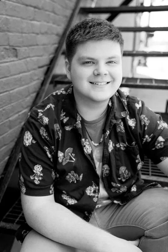 A young poses sitting on a fire escape in black and white