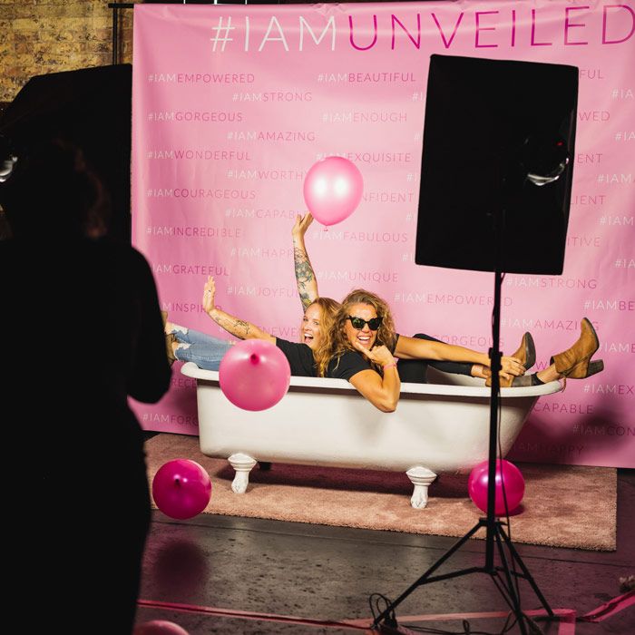 Two people in a bathtub in front of a booth backdrop